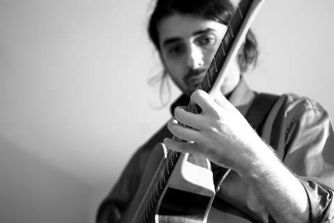 Lorenzo Spini behind the neck of his guitar, his hand on the fretboard in the foreground