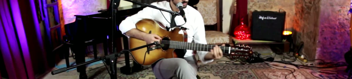 Lorenzo Spini playing and singing seated in a cellar lit by coloured lights