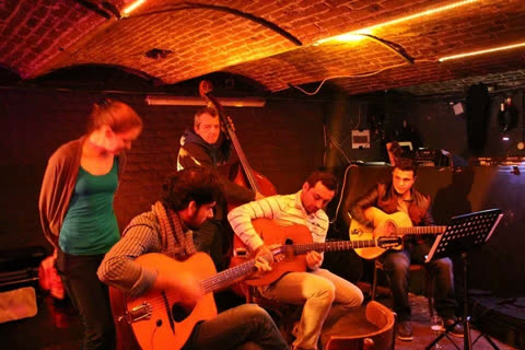 A gypsy jazz jam session in a brick-vaulted cellar