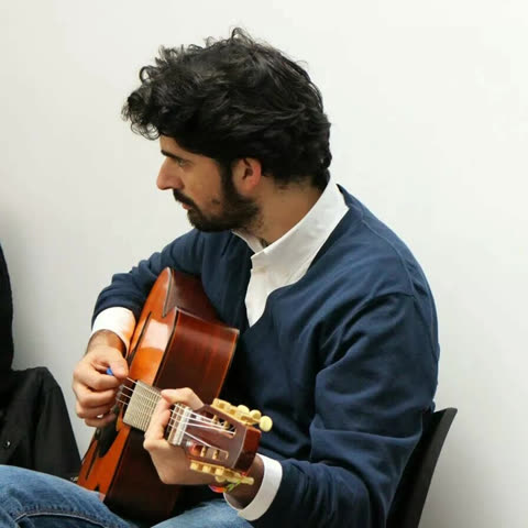 Lorenzo Spini playing a gypsy jazz guitar, seen in profile